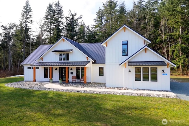 exterior space featuring metal roof, covered porch, a yard, board and batten siding, and a standing seam roof