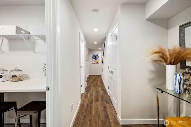 corridor featuring dark wood-type flooring, recessed lighting, and baseboards