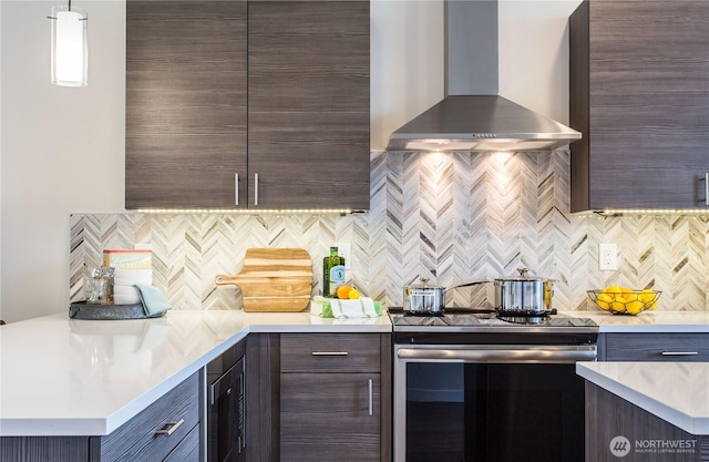 kitchen featuring electric stove, wall chimney range hood, and light countertops