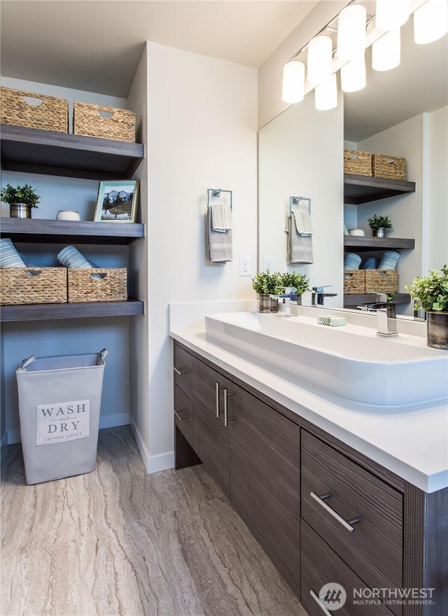 bathroom with marble finish floor, vanity, and baseboards