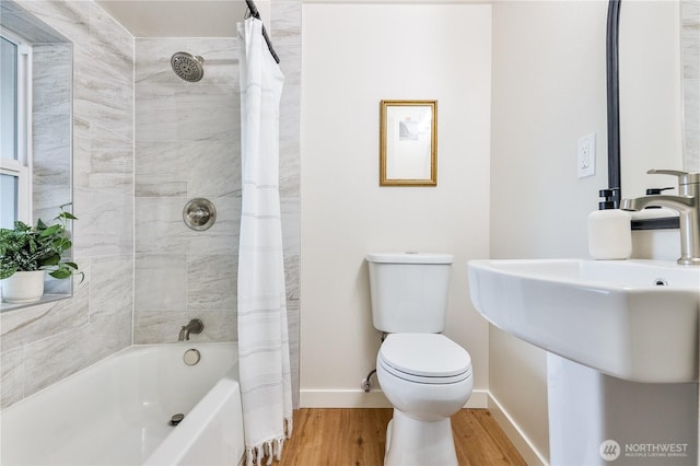 full bath with baseboards, toilet, wood finished floors, shower / bath combination with curtain, and a sink