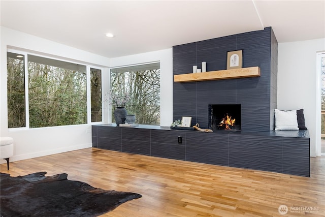 living room with recessed lighting, baseboards, light wood-type flooring, and a large fireplace