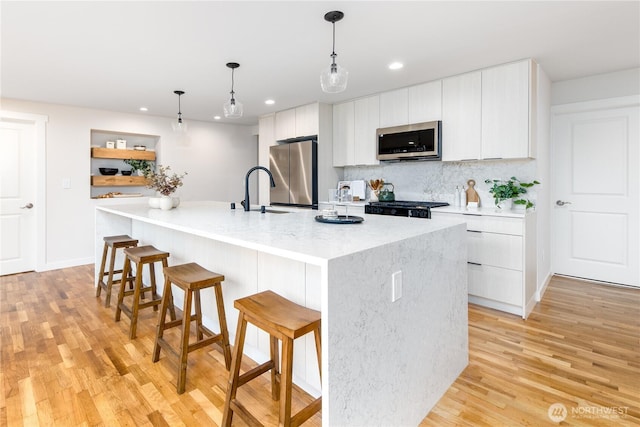 kitchen featuring a breakfast bar, white cabinetry, appliances with stainless steel finishes, and modern cabinets