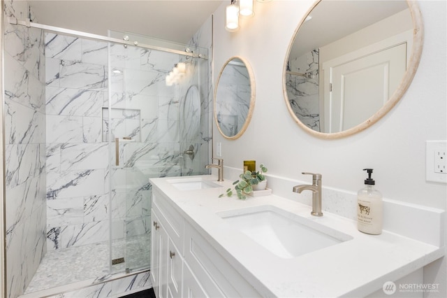 full bath featuring a sink, a marble finish shower, and double vanity