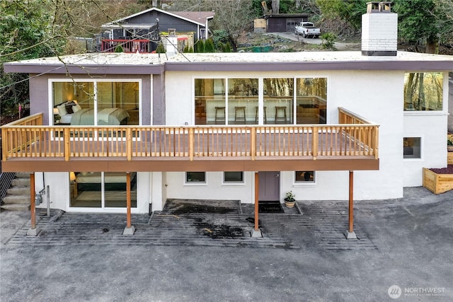 rear view of property with a chimney and stucco siding