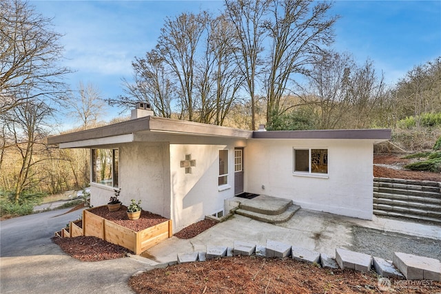 view of front of property featuring stucco siding and a chimney