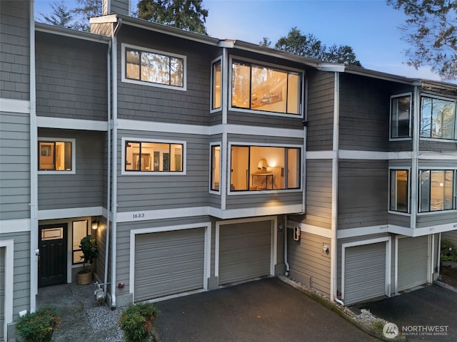 view of front of house featuring driveway, a garage, and a chimney