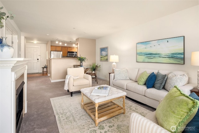 living area featuring a fireplace, baseboards, and light colored carpet