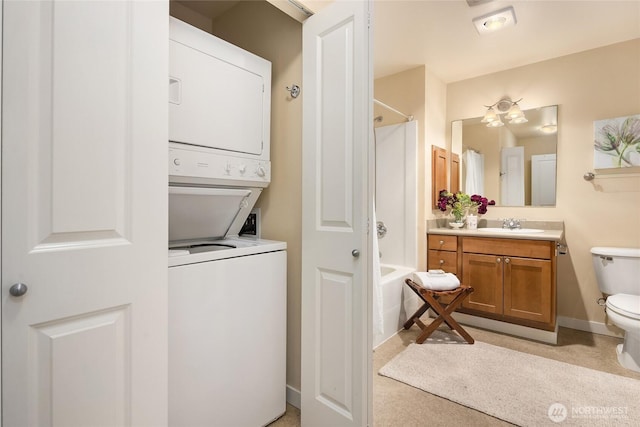 clothes washing area with laundry area, baseboards, a sink, and stacked washer and clothes dryer