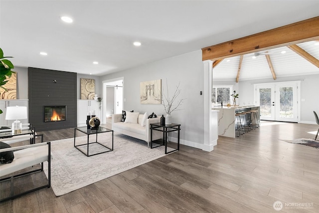 living room featuring a large fireplace, baseboards, lofted ceiling with beams, wood finished floors, and recessed lighting