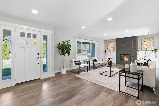 foyer entrance with a large fireplace, baseboards, wood finished floors, and recessed lighting