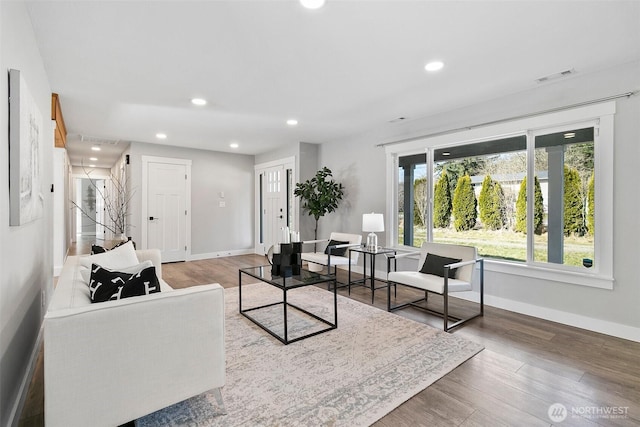 living area with baseboards, wood finished floors, and recessed lighting