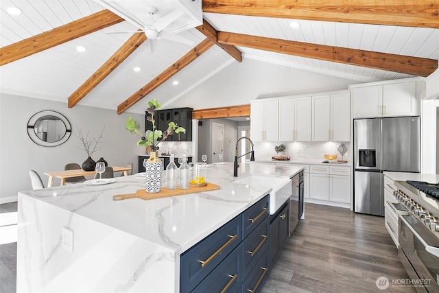 kitchen with stainless steel appliances, tasteful backsplash, white cabinets, a sink, and blue cabinets