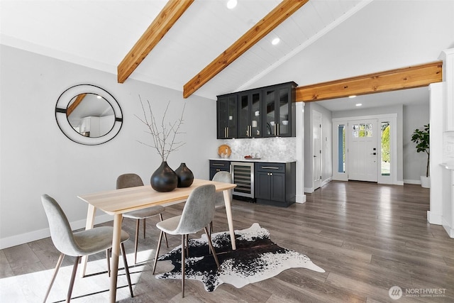 dining space featuring wine cooler, vaulted ceiling with beams, wood finished floors, bar area, and baseboards