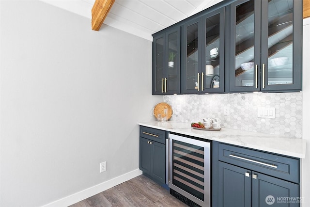 bar featuring beverage cooler, baseboards, backsplash, beam ceiling, and a bar