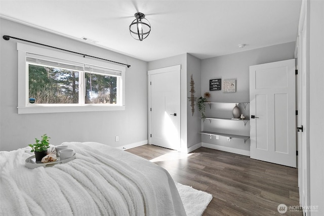 bedroom with wood finished floors, visible vents, and baseboards