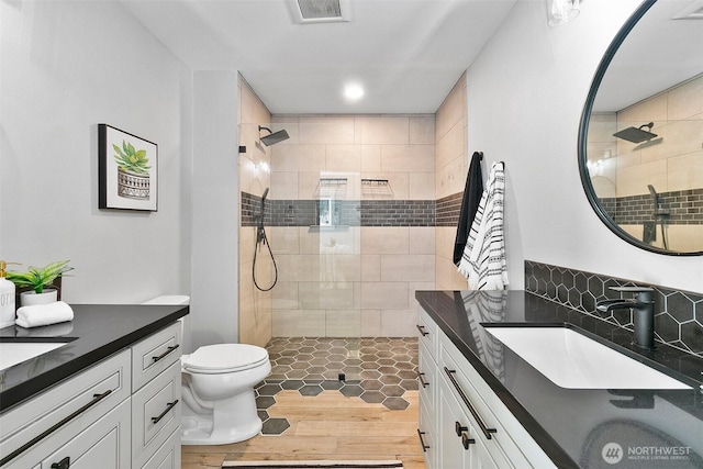 full bath with visible vents, tiled shower, and vanity