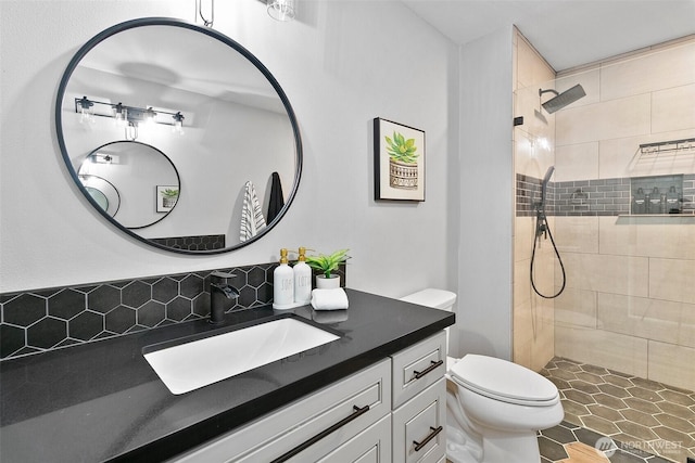 full bathroom with tiled shower, vanity, and toilet