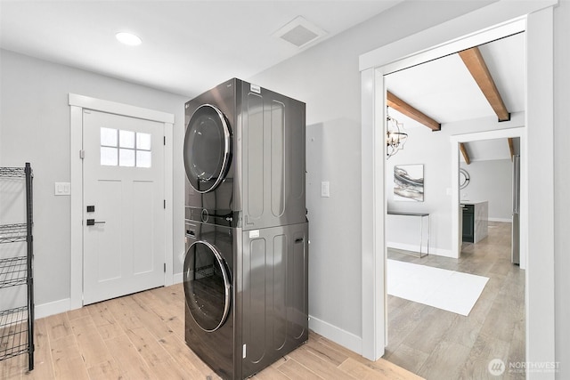 washroom with stacked washer and dryer, light wood-style flooring, and baseboards