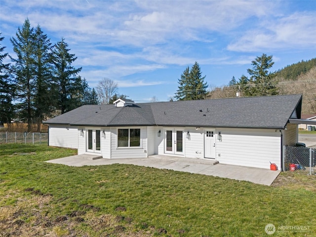 rear view of house featuring french doors, a patio area, a lawn, and fence