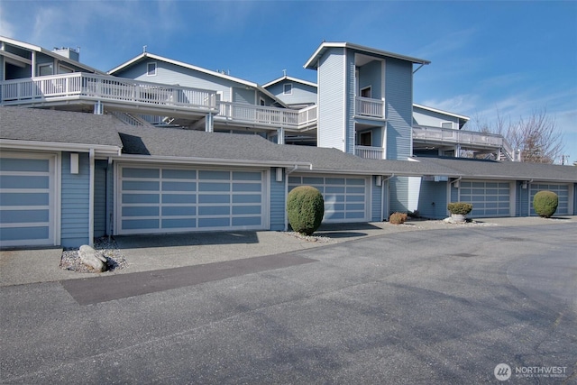 view of property with a garage and a shingled roof