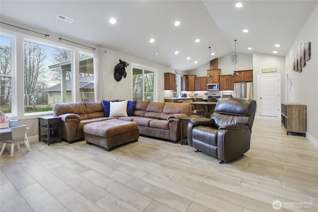 living room featuring a wealth of natural light, light wood-style flooring, visible vents, and baseboards