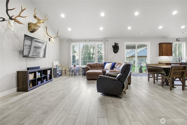 living room featuring light wood-type flooring, lofted ceiling, baseboards, and recessed lighting