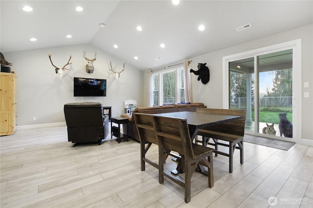 dining room featuring lofted ceiling, light wood-type flooring, visible vents, and baseboards