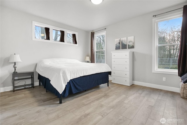 bedroom with light wood-type flooring, multiple windows, and baseboards