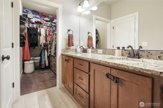 bathroom featuring double vanity, a spacious closet, and a sink