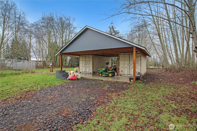 view of outbuilding with driveway, fence, and a carport