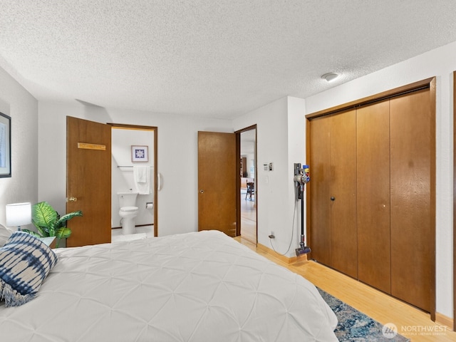 bedroom with light wood-type flooring, a textured ceiling, a closet, and ensuite bathroom