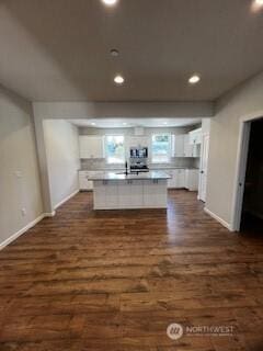 kitchen with dark wood-style floors, light countertops, stainless steel microwave, and white cabinetry