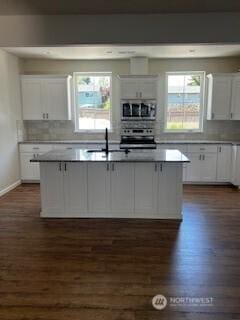 kitchen with light countertops, an island with sink, and white cabinets