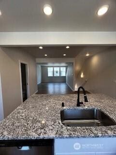 kitchen with light stone counters, recessed lighting, stainless steel dishwasher, open floor plan, and a sink