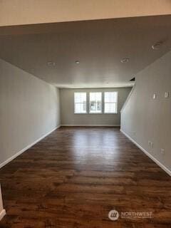 spare room featuring dark wood-style flooring and baseboards