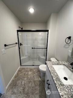 full bath featuring toilet, a stall shower, baseboards, and vanity