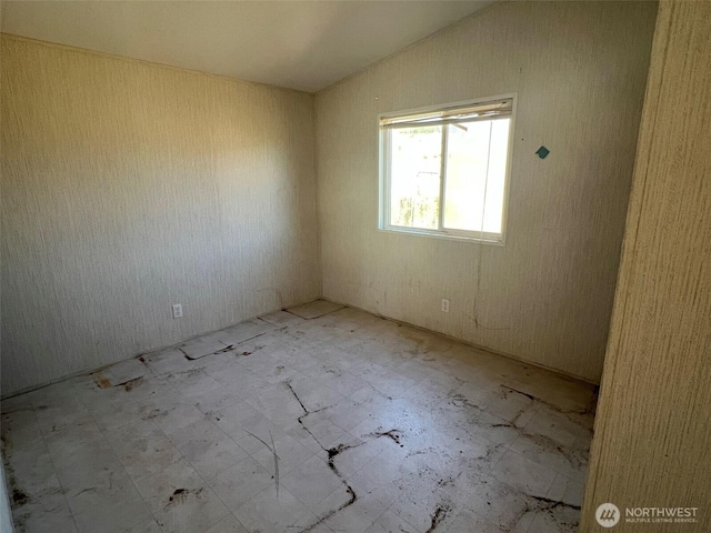 unfurnished room with lofted ceiling and tile patterned floors