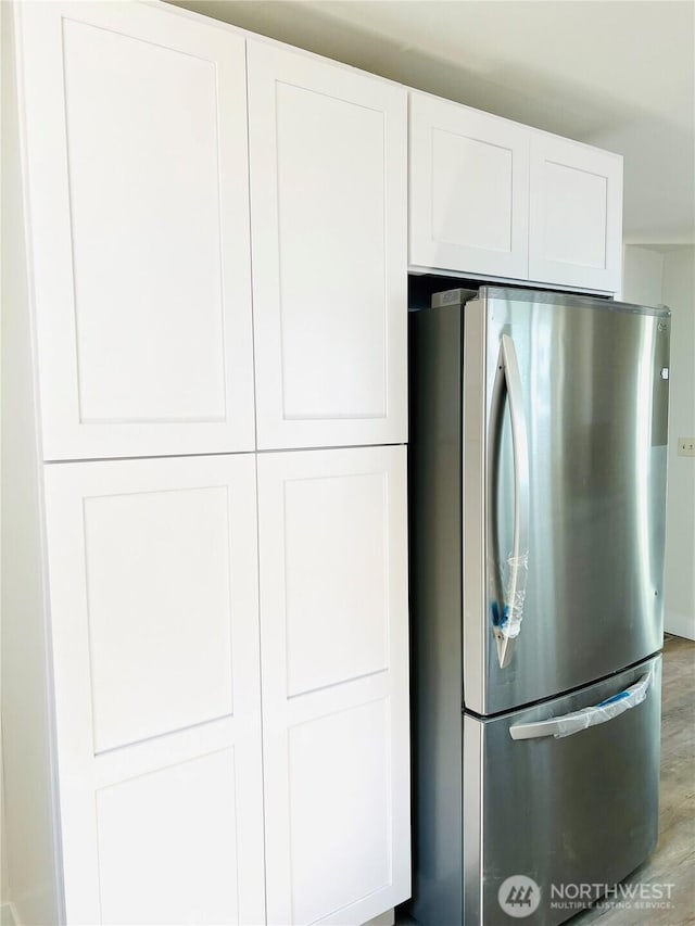 kitchen featuring light wood-style flooring, freestanding refrigerator, and white cabinetry