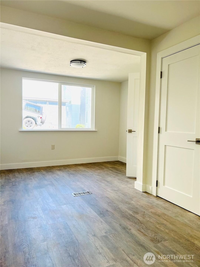 empty room featuring visible vents, baseboards, and wood finished floors