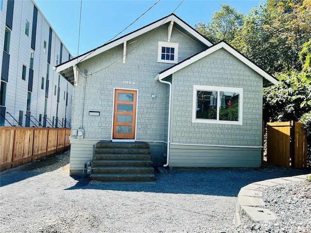 rear view of house with entry steps and fence