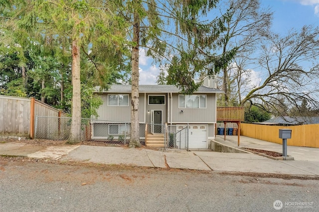 bi-level home featuring driveway, a garage, and a fenced front yard