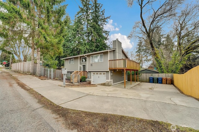 view of front of house with an attached garage, a chimney, concrete driveway, and fence private yard