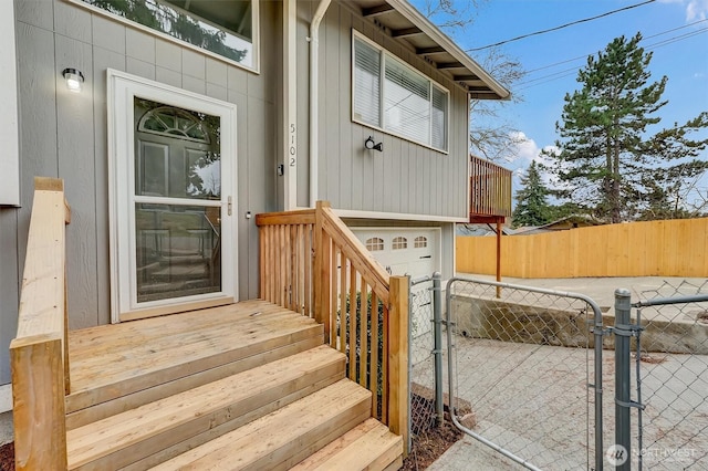 property entrance featuring a gate, an attached garage, and fence
