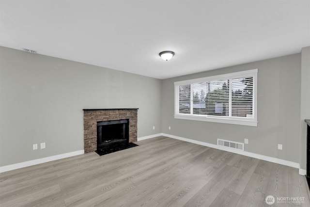 unfurnished living room with baseboards, a fireplace, visible vents, and wood finished floors