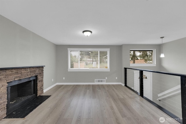 unfurnished living room with wood finished floors, baseboards, a fireplace, and visible vents