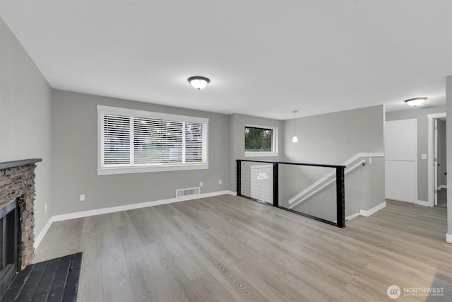 unfurnished living room with baseboards, a fireplace, visible vents, and wood finished floors