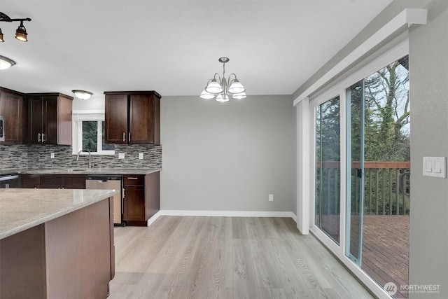 kitchen featuring tasteful backsplash, hanging light fixtures, dishwasher, light wood-style flooring, and dark brown cabinets