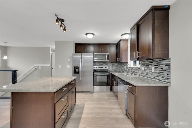 kitchen with tasteful backsplash, a center island, a sink, dark brown cabinetry, and appliances with stainless steel finishes