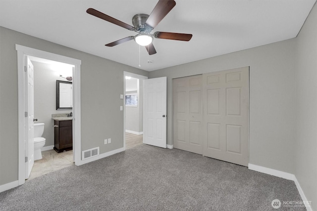 unfurnished bedroom featuring a closet, carpet flooring, ensuite bathroom, visible vents, and baseboards